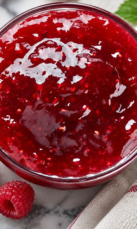 Raspberry filling: glossy raspberry compote with seeds in a glass bowl, fresh raspberries beside it